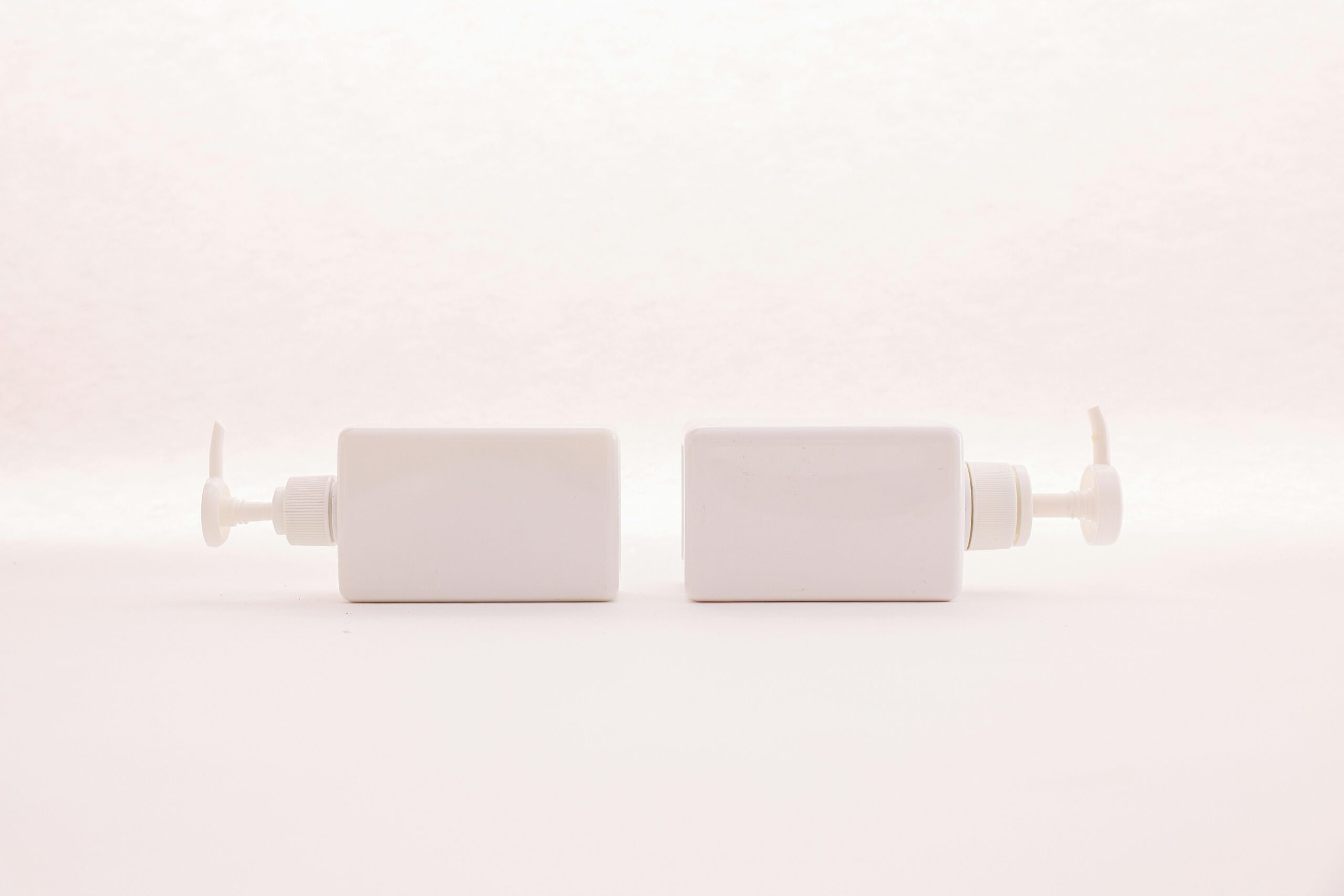 Simple and elegant white pump bottles on a clean white background, perfect for beauty product mockups.